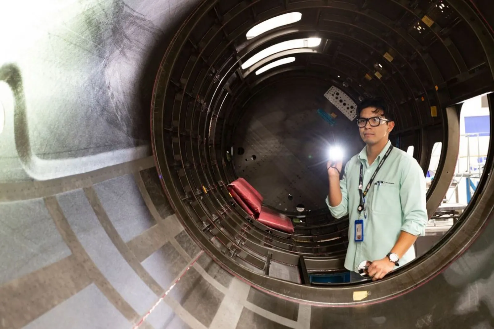 Técnico revisando el interior de un fuselaje con lámpara de mano