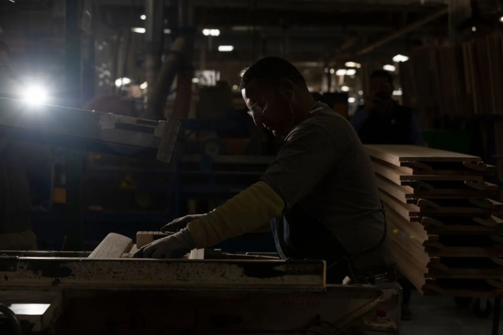Operario trabajando en línea de producción con iluminación dramática