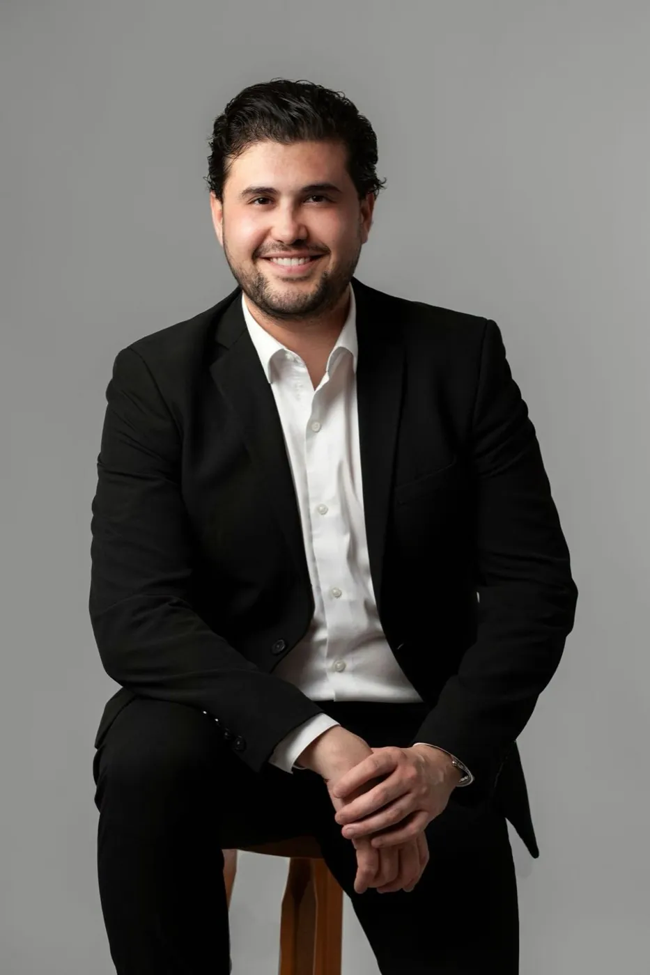 Retrato corporativo de un directivo sentado sobre fondo gris